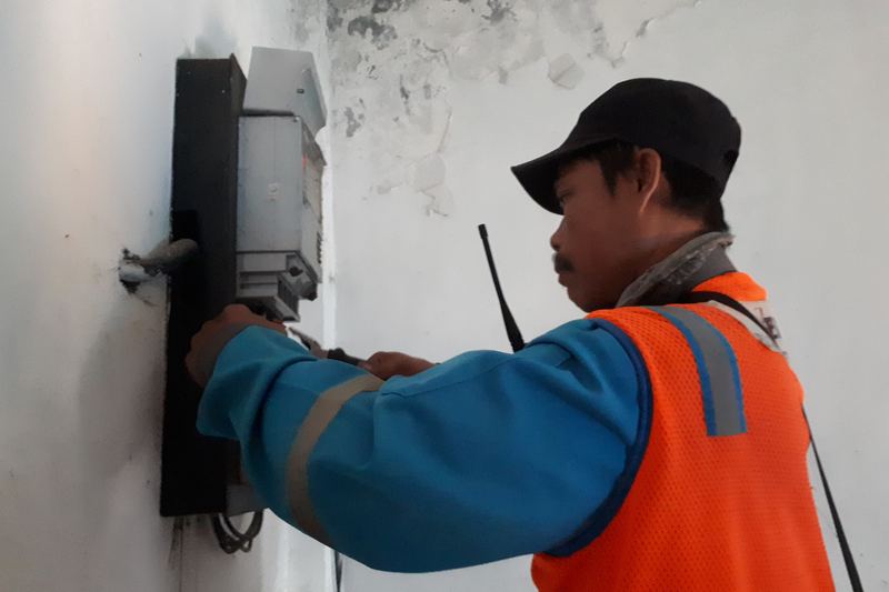 Side view of electricians fixing an electricity meter